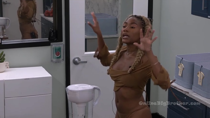 Taylor gesturing animatedly while talking to Jason in the Big Brother house kitchen area