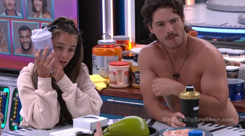 Houseguests chatting in the Big Brother kitchen area surrounded by protein supplements and food