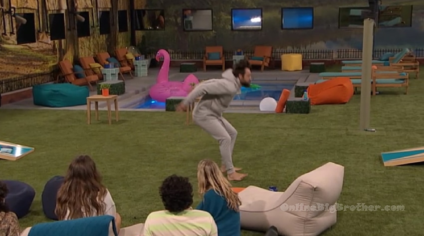 Kamu doing back flips in the Big Brother backyard while houseguests watch from bean bag chairs on the grass