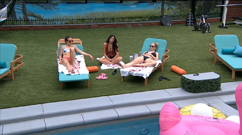 Three houseguests chat by the Big Brother backyard pool on lounge chairs