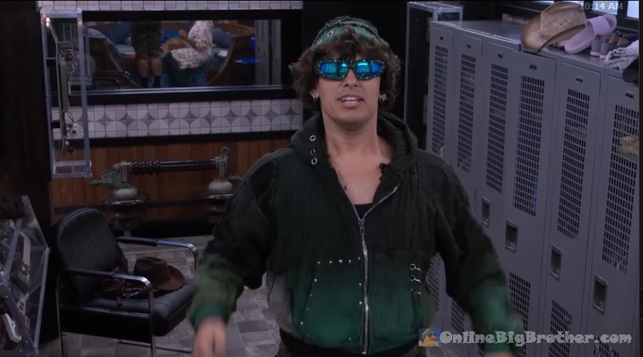 Jason goofing around in the Big Brother house wearing blue mirrored sunglasses and a green hoodie at 10:14 AM
