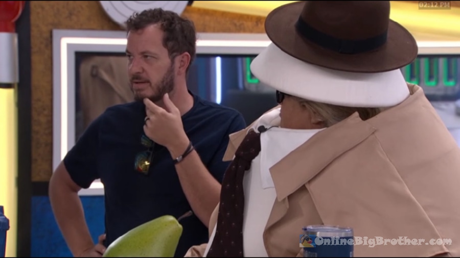 Devens talking with a houseguest wearing a trench coat, tie, and wide-brim fedora in the Big Brother house at 2:11 PM