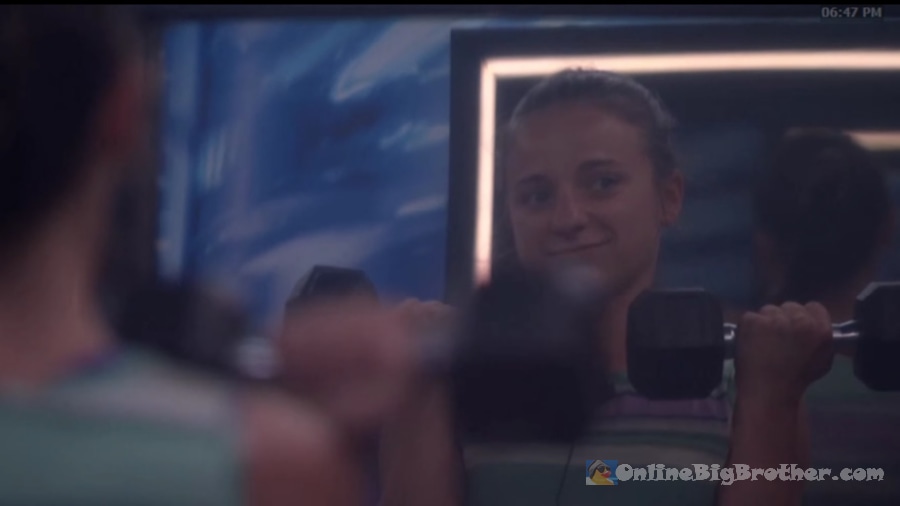 Mallory lifting dumbbells in the gym, smiling at her reflection in the mirror at 6:47 PM