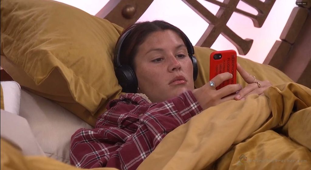 Haley lies on the HOH bed wearing headphones, missing the entire confrontation happening beside her