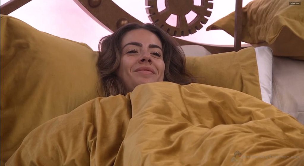 Dee watches the HOH spy screen from bed as Taylor climbs the stairs toward the HOH room